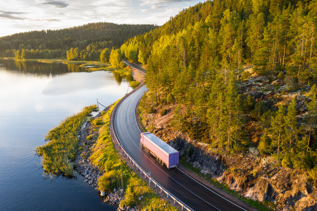 Veok sõidab mööda käänulist maanteed läbi metsase järvemaastiku.